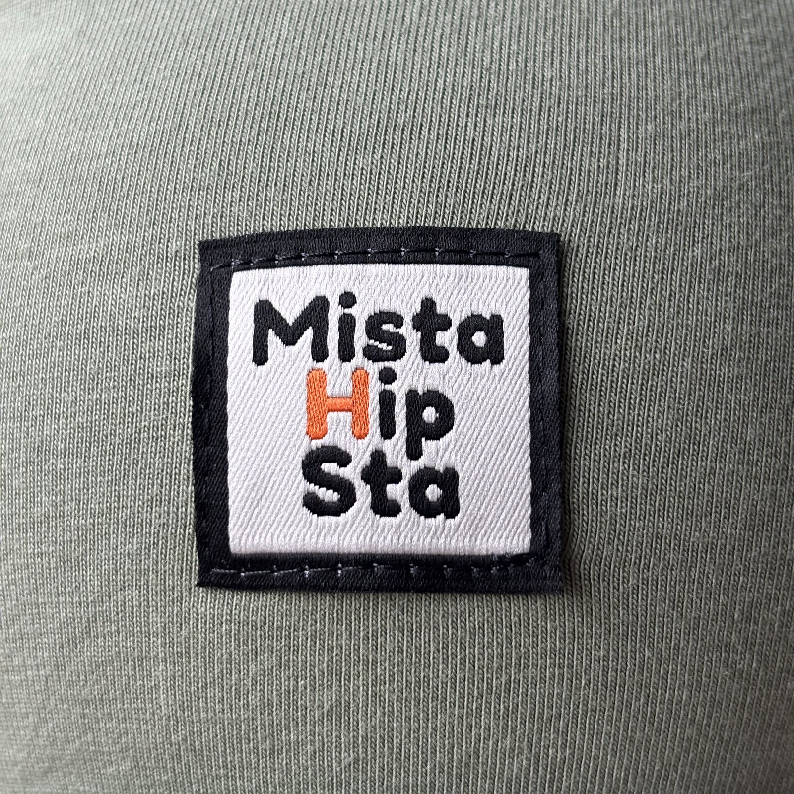 Naszywka MistaHipsta z pomarańczowym H na oliwkowej czapce beanie